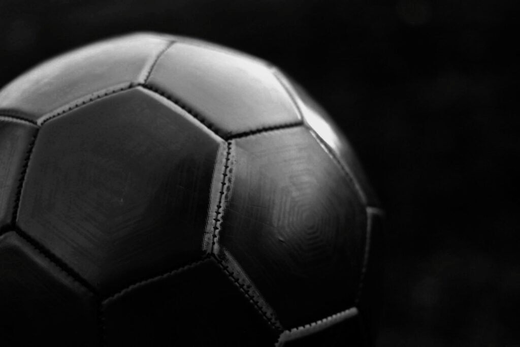 Close-up of a dark leather football showing the stitched seams between its curved panels