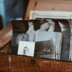 A wooden box on a table filled with old black and white photographs and card-mounted portraits, one of them leaning against the front edge of the box