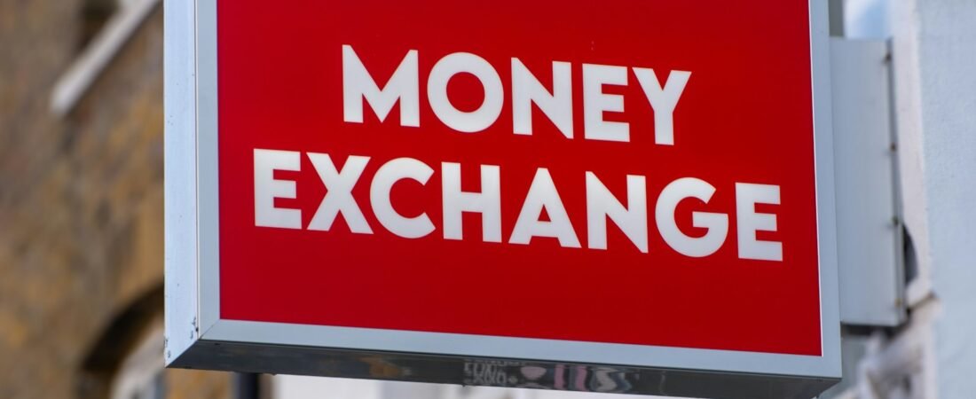 A red illuminated sign reading MONEY EXCHANGE in white capital letters, mounted on the front of a building
