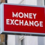 A red illuminated sign reading MONEY EXCHANGE in white capital letters, mounted on the front of a building