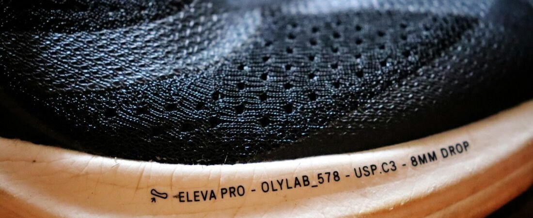 Extreme close-up of a running shoe midsole, with the foam stack and its printed specification legible along the edge
